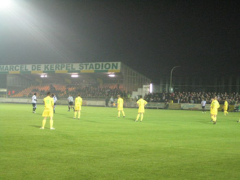 Im Hintergrund die einzige Sitzplatztribüne im Stadion Marcel de Kerpel